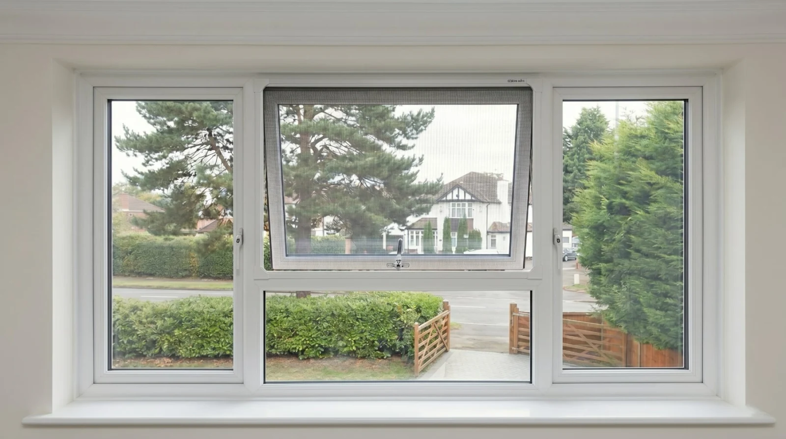 Magnetic flyscreen window fitted to a top-hung UPVC window in a UK home, view out to the front garden